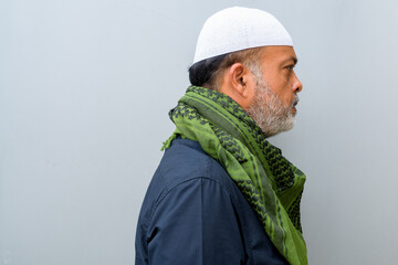 Portrait of handsome bearded muslim man against plain wall