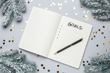 Word Goals written in notebook and Christmas decor on light grey background, flat lay
