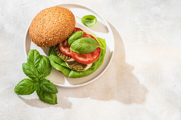 Caprese sandwich with fresh tomatoes, mozzarella cheese, pesto and basil leaves on a white plate. A healthy snack. Healthy food concept.