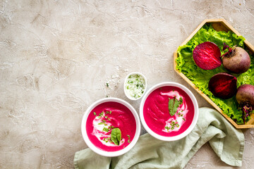 Fototapeta na wymiar Red beet soup in white bowl with raw beet roots
