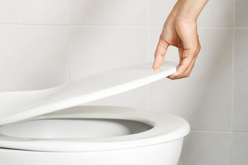 man's hand opening the toilet lid