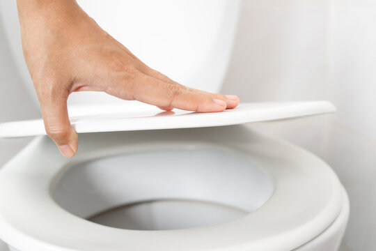 Woman's hand opening the toilet lid