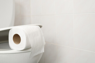 The toilet paper is on the toilet flush at home.