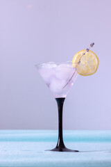 Cocktail glass with ice and lavender lemonade on lilac background