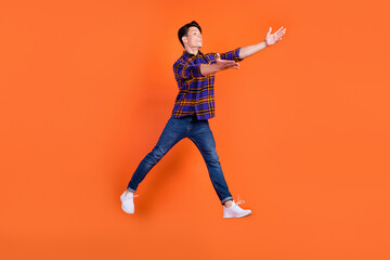 Fototapeta na wymiar Full length profile photo of millennial guy jump hug wear shirt jeans sneakers isolated on orange background