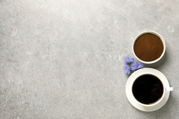 Cup of delicious chicory drink, powder and flowers on light grey table, flat lay. Space for text