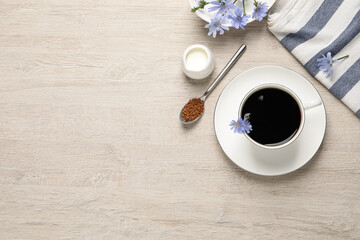 Fototapeta na wymiar Cup of delicious chicory drink, granules and flowers on light wooden table, flat lay. Space for text