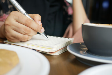 Fototapeta na wymiar Close up of women hand writing on notepad.