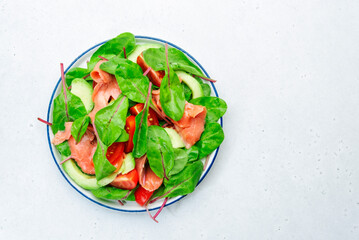 Salmon avocado salad, beet leaves, radicchio, tomatoes, lemon and olive oil dressing for keto and low card diet. Gray background, top view