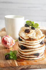 Pile of freshly cooked pancakes with blueberries on white background, morning breakfast meal