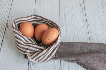 Brown chicken eggs lay on the wooden floor with brown fabric, vintage style.
