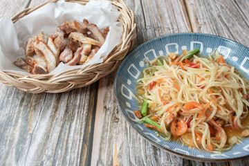 Grilled pork collar in the wooden basket with Papaya salad.