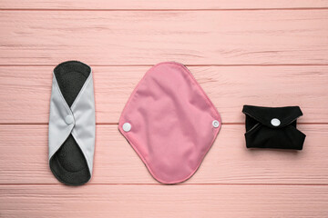 Many reusable cloth menstrual pads on pink wooden table, flat lay © New Africa