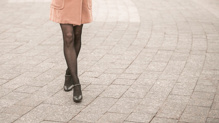 No face close up on legs making a cat walk of young woman on the street wearing autumn black shoes....