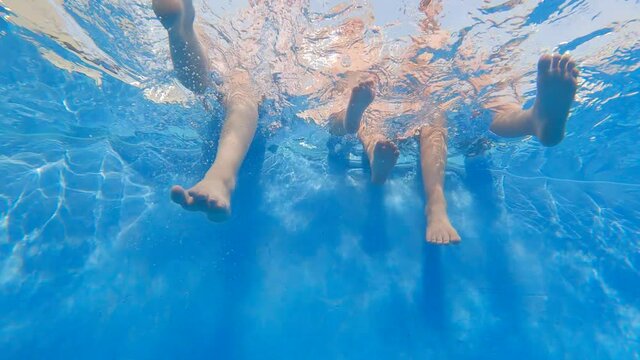 Slow motion of three kids with their legs put into the water of a swimming pool and having fun - 29.97fps