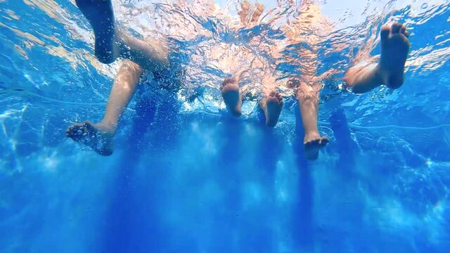 Slow motion of three kids with their legs put into the water of a swimming pool and having fun - 59.94fps
