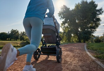 Active mother jogging. Jogging or power walking woman with a baby stroller in morning. Mother with child in stroller running