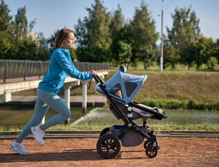 Active mother jogging. Jogging or power walking woman with a baby stroller in morning. Mother with...