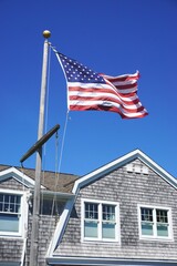 American flag flying on a nautical mast flagpole in front of a typical New England building with...