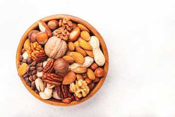 Nut mix in bowl. Almonds, hazelnuts, walnuts and other. Healthy food snack mix on white table, top view, copy space