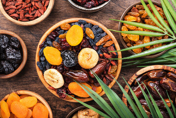 Dried fruits bowl. Healthy food snack: sun dried organic mix of apricots, figs, raisins, dates and other on wooden table, top view