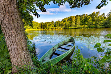Beautiful summer landscape with green boat and lake
