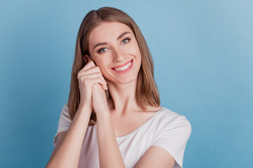 Fototapeta premium Portrait of adorable dreamy girl toothy shiny smile hands cheeks on blue background