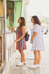 2 young spanish women waiting for an ice cream