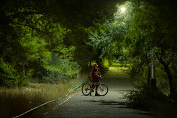 Fototapeta na wymiar a girl with a bicycle in a night park