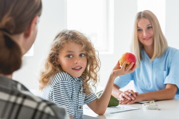 Little boy playing with fruit during a visit to a dietitian
