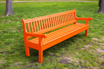 Bright orange wooden bench in the park.