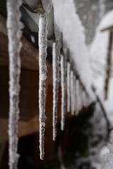 Eiszapfen an Hausdach im Winter mit Schnee