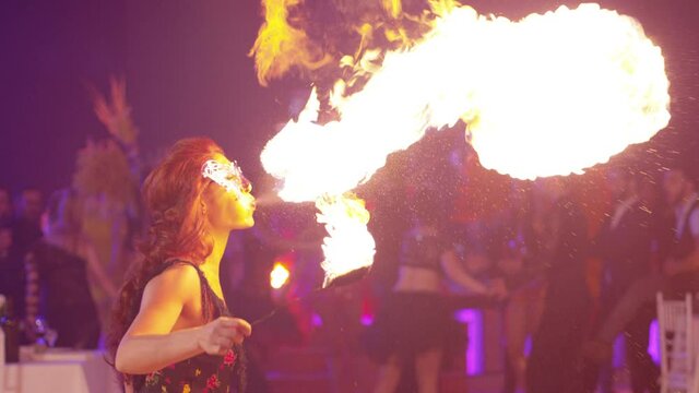 Fantastic show at party . Young woman is spraying kerosene on fire torch and erupting flame. Fire performer blowing fire. Circus performer emits fire out of her mouth. Shot on Red Dragon. Slow Motion
