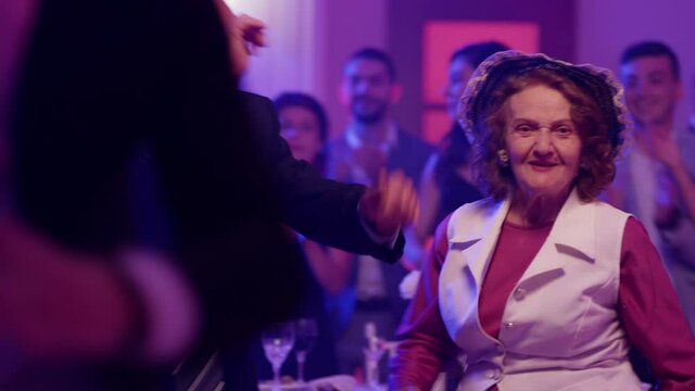 Stylish elderly couple having fun dancing at a colorful party . Sweet senior couple smiling and partying during party . Active retirement . Shot on RED HELIUM Cinema Camera	