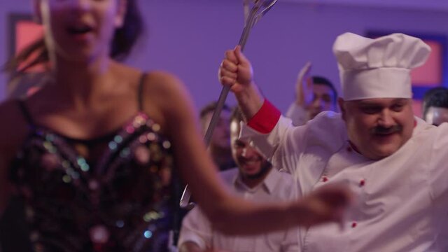 Cook dancers having fun dancing at a colorful party . Funny cook chef in white uniform, with a hat and ladle , smiling and partying during party . Shot on RED EPIC Cinema Camera	