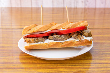 Roast pork sandwich with sliced tomato and mayonnaise on formica table