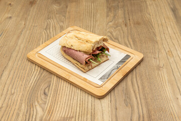 Great pastrami sandwich with arugula and rustic bread on a bamboo board