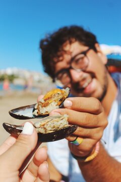 Portrait close up of a person holding stuffed mussels , traditional turkish beach food, at sunny day 