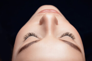 Eyelash extension procedure top view. Woman eye with beauty black lashes