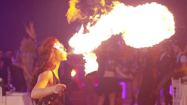 Fantastic show at party . Young woman is spraying kerosene on fire torch and erupting flame. Fire performer blowing fire. Circus performer emits fire out of her mouth. Shot on Red Dragon. Slow Motion 
