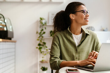 Young black woman working with laptop while sitting at cafe