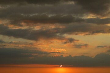 Fototapeta na wymiar Orange dark dramatic sunset with black clouds in the sky, natural sunset background 