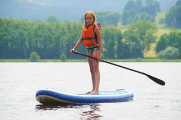 Paddle boarder. Child girl paddling on stand up paddleboard. Healthy lifestyle. Water sport, SUP...