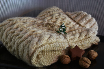 Zopfpullover aus Schafwolle als Weihnachtsgeschenk mit Masche und Keramik Weihnachtsbaum, Farben Braun, Weiß, grauer Hintergrund