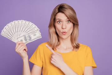 Photo of young pretty woman amazed shocked point finger dollars cash recommend select isolated over...