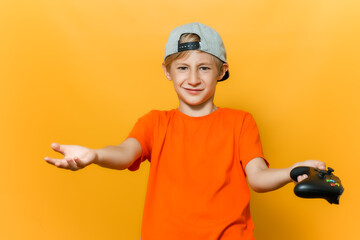 a boy in a cap and an orange T-shirt spread his hands in different directions he holds a gamepad in one hand © Roman