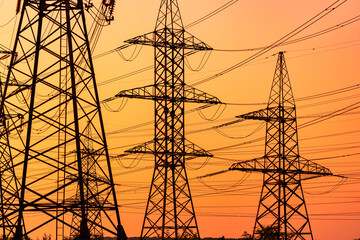 Sunset silhouette energy constructions. Shadows of high voltage electric lines.
