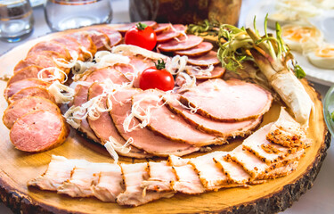 A variety of sausages and ham on a wooden board