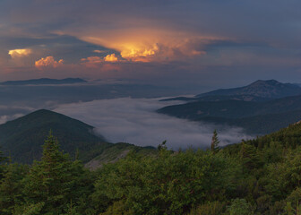 Sun-colored clouds. Fog floats over the mountains. 