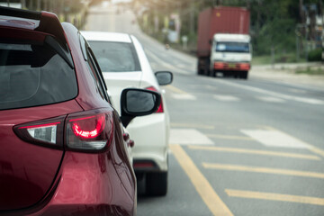 Rear side of red car driving on the asphalt road in the city. During daytime. Several cars across the street ran. with open brake light.